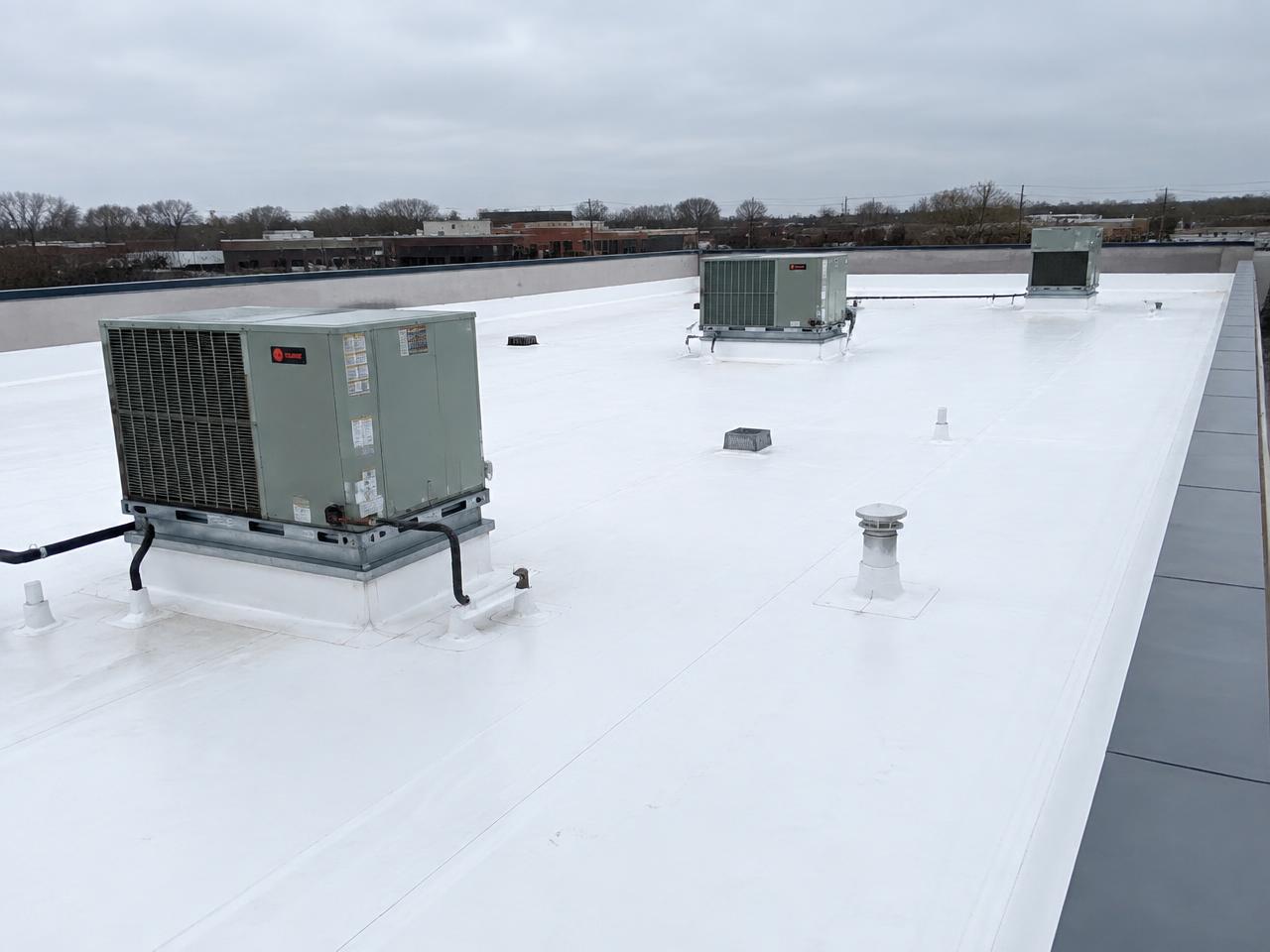 White commercial flat roof with rooftop HVAC units and parapet walls