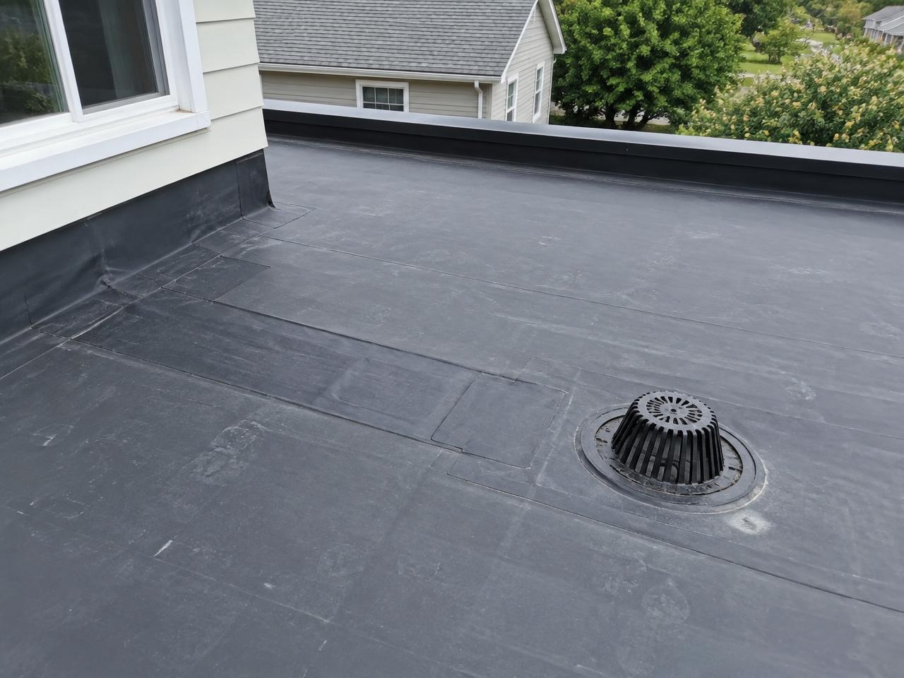 Low slope rubber roof with a patched seam and a roof drain