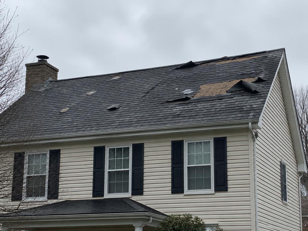 Asphalt shingle roof with missing and curling shingles
